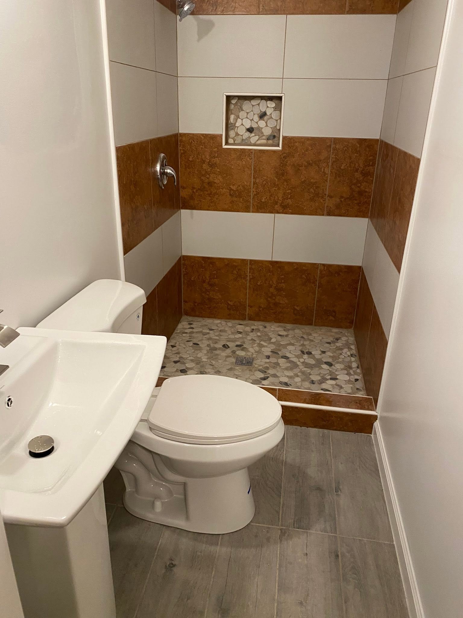 Completed bathroom addition with terracotta tile shower surround, pebble floor, pedestal sink and wood-look floor tile — Metro Atlanta, GA