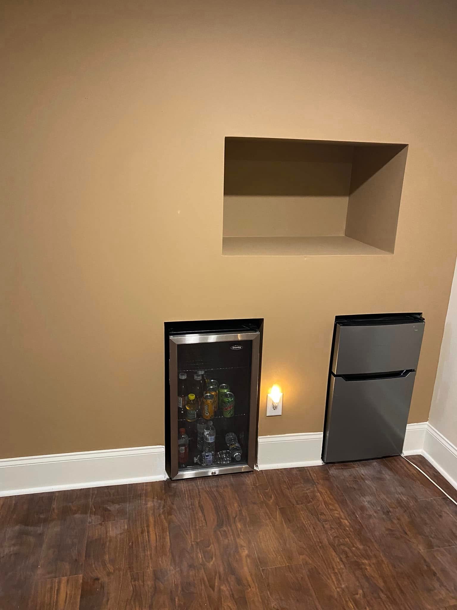 Completed custom wall niches painted warm tan with built-in mini fridges and dark LVP flooring — Metro Atlanta, GA