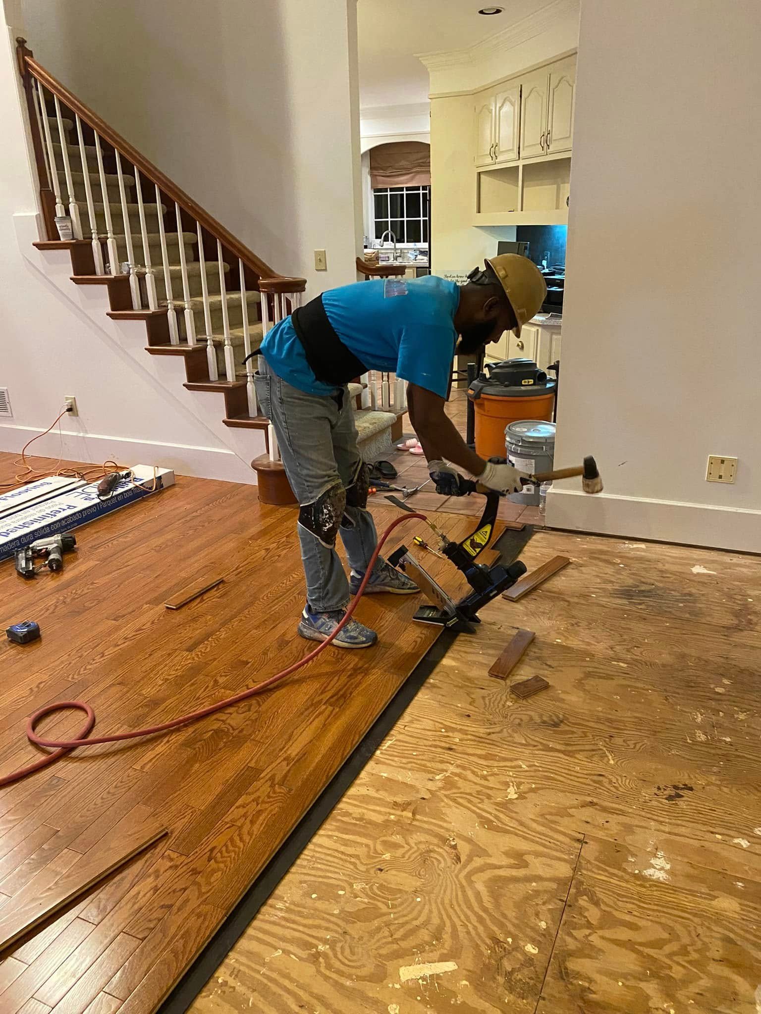 Richard nailing down red oak hardwood planks with pneumatic floor nailer during installation — Metro Atlanta, GA