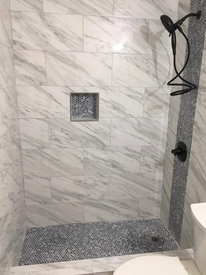 Marble-look porcelain shower with recessed shampoo niche, penny tile floor and oil-rubbed bronze shower head — Metro Atlanta, GA