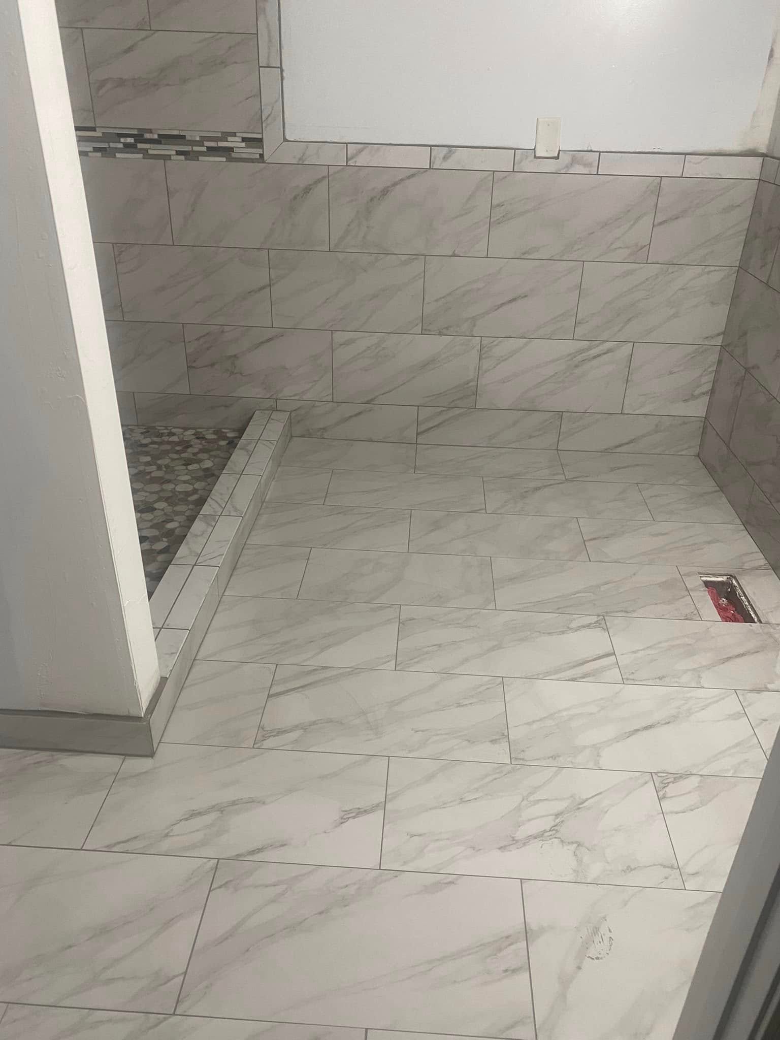 Walk-in shower build — large format marble-look tile on floor and walls, pebble stone bench seat and linear glass mosaic accent strip — Metro Atlanta, GA