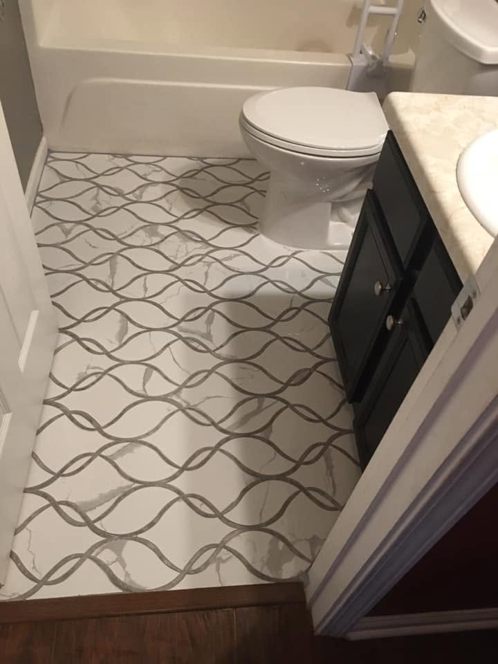 Full bathroom floor covered in decorative wave pattern porcelain tile with white marble background and taupe wave design — Metro Atlanta, GA